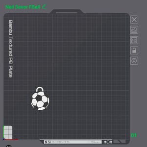 May include: A digital interface showing a Bambu Textured PEI Plate with a grid pattern. A small, white and black soccer ball charm with a silver loop is positioned on the grid. The text Nail Saver FBall is visible at the top left corner.
