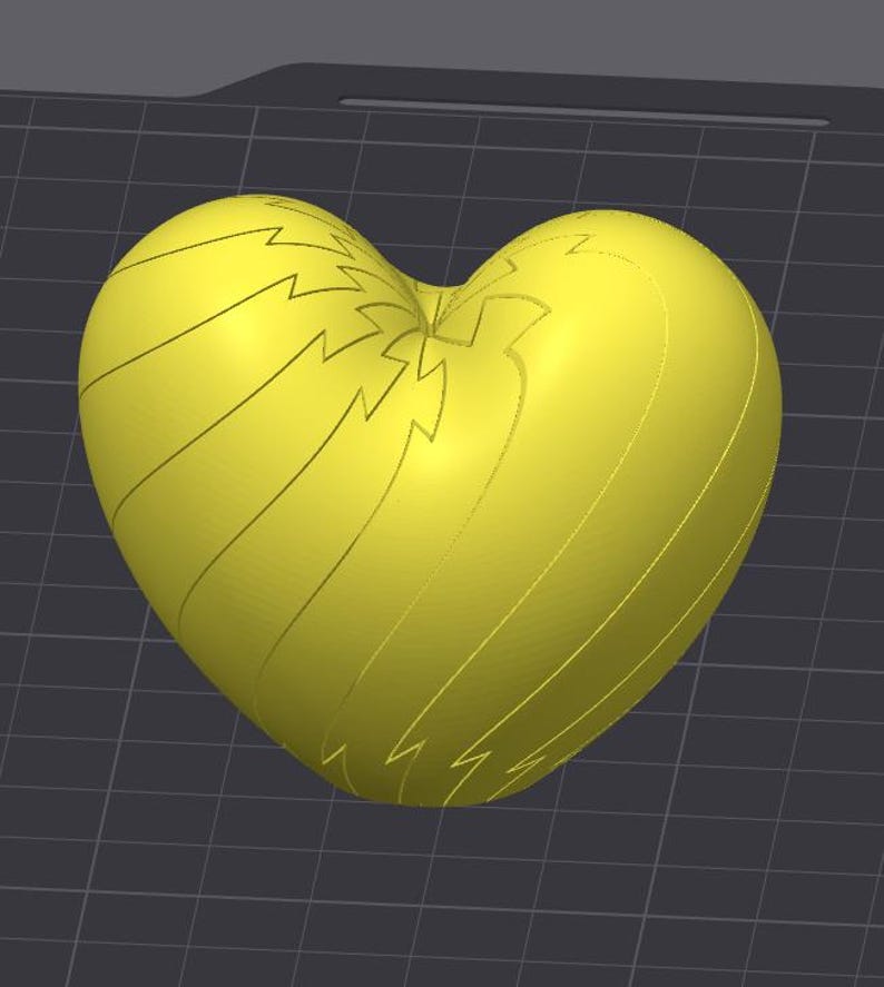 May include: A bright yellow, heart-shaped 3D model featuring a series of engraved lightning bolt patterns that curve along the surface. The object is displayed against a dark gray grid background, highlighting its smooth, rounded form and symmetry.