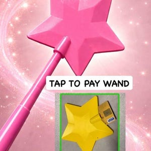 Puede incluir: Una varita mágica rosa en forma de estrella con el texto "TAP TO PAY WAND". La varita tiene un mango y una cabeza en forma de estrella. También se muestra un objeto amarillo en forma de estrella con una tarjeta de crédito.