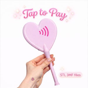 May include: A light pink heart-shaped fan with a handle, featuring a pink wireless payment symbol. The text "Tap to Pay" is above the fan. The image also includes the text "STL 3MF files".