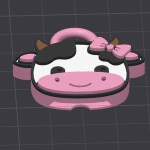 May include: A pink and black cow-shaped keychain with a bow on its head. The keychain has a white face with black spots, brown horns, and a pink nose. The keychain is made of a hard material.