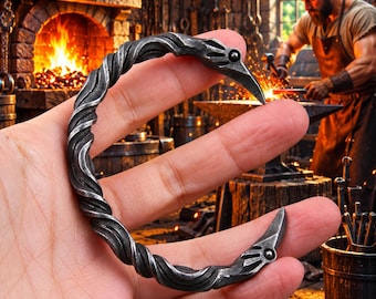 May include: A dark gray metal cuff bracelet featuring a twisted, rope-like texture throughout the band. The two ends of the bracelet are shaped like stylized bird heads, each accented with a small, circular rivet detail on the side.