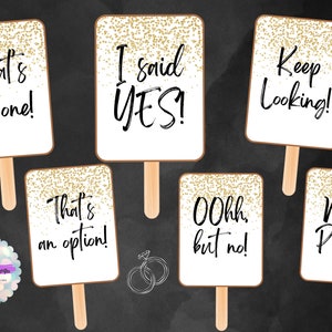 May include: Set of 8 gold glitter photo booth props with white backgrounds and black text. The text on the props reads: "That's the one!" "I said YES!" "Keep Looking!" "That's an option!" "Oohh but no!" "Next Please!"