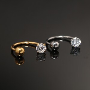 Anello a ferro di cavallo rotondo con sfera incastonata a griffe in titanio G23 ipoallergenico con finitura dorata, filettatura interna, per setto nasale e conchiglia, calibro 16G.