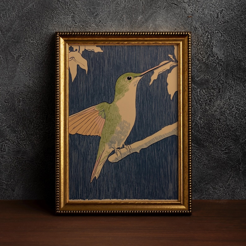 May include: A framed print featuring a hummingbird perched on a branch. The bird has green and tan plumage with outstretched wings. The background is a dark blue with a wood grain texture, and the frame is gold.