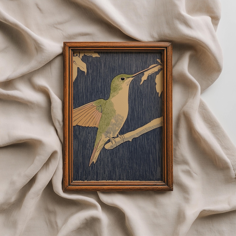 May include: A framed print featuring a hummingbird perched on a branch. The bird has green and tan plumage, with wings slightly spread. The background is a dark blue, and the frame is made of wood.