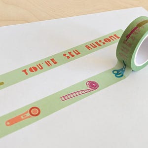 May include: A roll of light green washi tape with sewing-themed illustrations and the text "YOU'RE SEW AWESOME" in red. The tape features images of scissors, needles, and measuring tape.