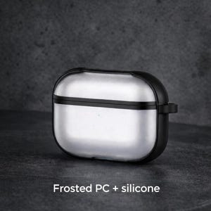 A silver and black earbud case with a frosted PC+ silicone design, sitting on a dark surface.
