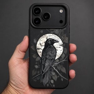 May include: A black smartphone case featuring a detailed illustration of a raven perched on a branch. The bird is centred against a circular, stained-glass style background with light-coloured segments, surrounded by dark, leafy foliage.
