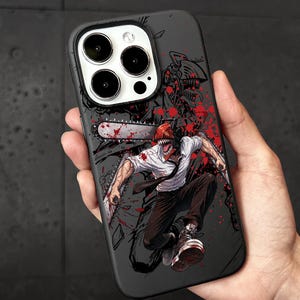 Op de afbeelding: Zwarte telefoonhoes met een dynamische illustratie van een personage met een kettingzaagkop en een kettingzaagwapen, met rode spat-effecten. De hoes heeft een glanzende afwerking en een camera-uitsparing.