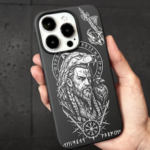 May include: A black smartphone case featuring a white line art illustration of a bearded warrior wearing a wolf headdress, accompanied by a raven, a compass symbol, and runic inscriptions. The design includes a spear and a skull motif at the top.