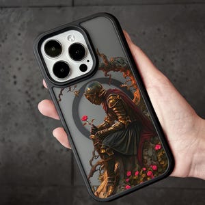 A person holding a phone case with a detailed illustration of a knight in armor, surrounded by flowers and foliage.