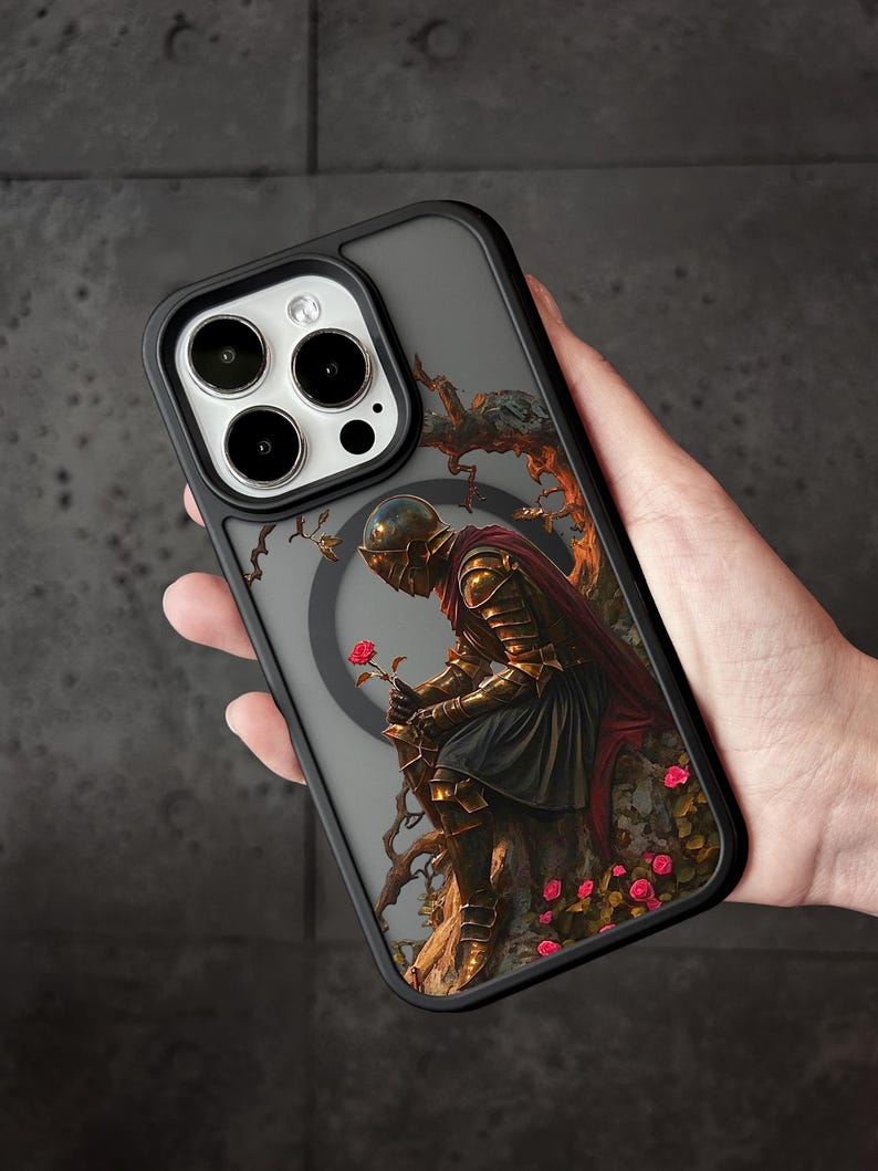A person holding a phone case with a detailed illustration of a knight in armor, surrounded by flowers and foliage.