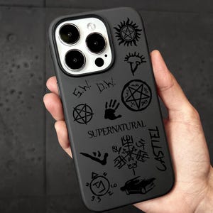 May include: Black phone case featuring various symbols and the word "Supernatural" in a stylized font. The case also includes the name "Castiel" and other graphic elements.