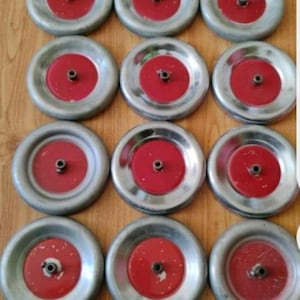 Könnte beinhalten: Zwölf silberfarbene Metallräder mit roten Zentren. Jedes Rad hat ein kleines Loch in der Mitte.