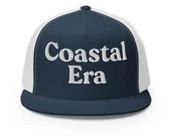 Op de afbeelding: Marineblauwe en witte truckerpet met de geborduurde tekst "Coastal Era" in het wit. De pet heeft een mesh achterkant en een gebogen klep, ideaal voor bescherming tegen de zon.