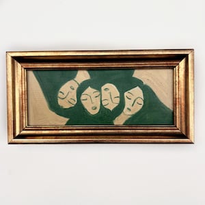 K&ouml;nnte beinhalten: Abstraktes Gem&auml;lde in einem goldfarbenen Rahmen. Das Kunstwerk zeigt f&uuml;nf stilisierte Gesichter mit geschlossenen Augen und dunkelgr&uuml;nem Haar vor einem hellbeigen Hintergrund. Der Rahmen hat ein detailliertes, strukturiertes Aussehen.