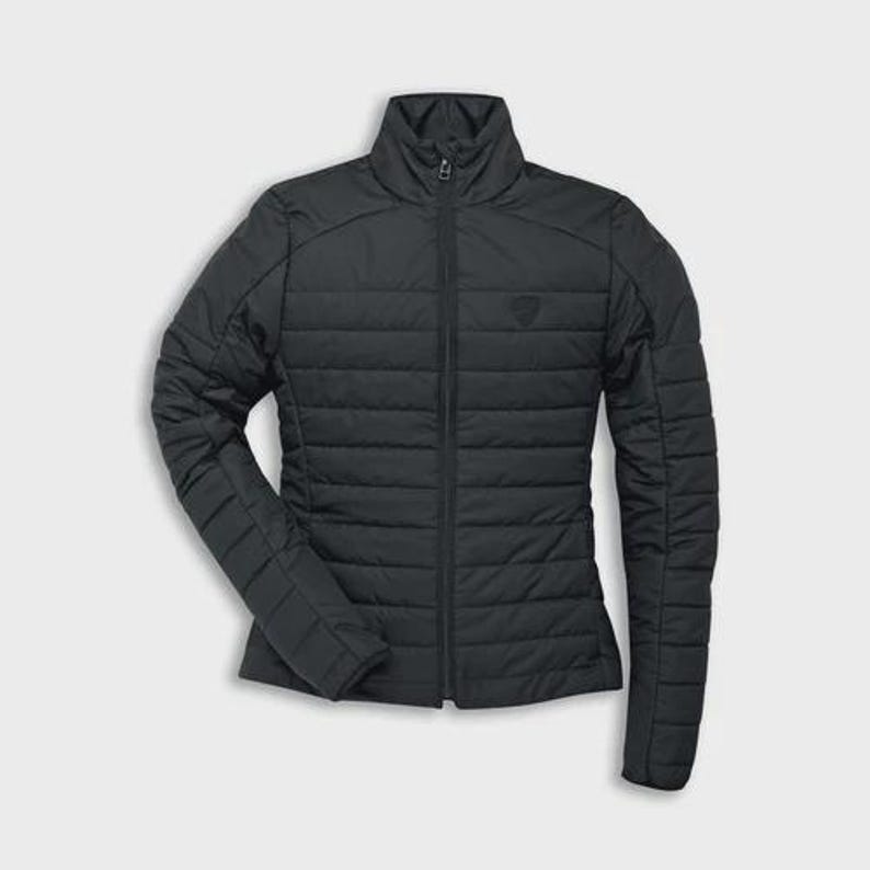 May include: A black quilted jacket with a high collar and a full-length zipper. The jacket has a subtle logo on the chest and features horizontal stitching across the body and sleeves. The jacket is designed for a sleek, streamlined fit.