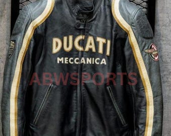 May include: Black leather motorcycle jacket with the word "DUCATI MECCANICA" in gold lettering. The jacket has gold and white stripes down the sleeves and a small patch on the upper arm. The jacket is hanging on a black hanger.