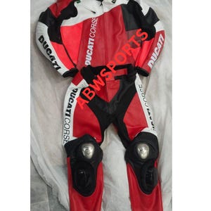 May include: Red, white, and black Ducati motorcycle racing suit. The suit is made of leather and features the Ducati Corse logo on the chest, arms, and legs. Includes knee and elbow protection.