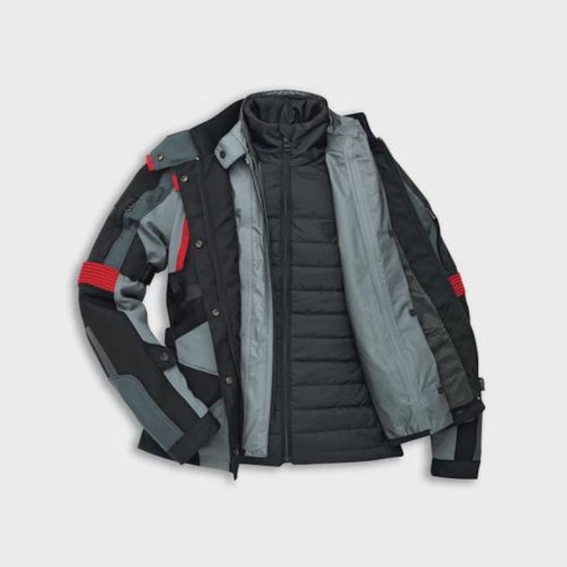 May include: A black and gray motorcycle jacket with red accents. The jacket has a quilted inner layer and a high collar. The sleeves feature gray and black panels with red stripes. The jacket is open, revealing the interior lining.