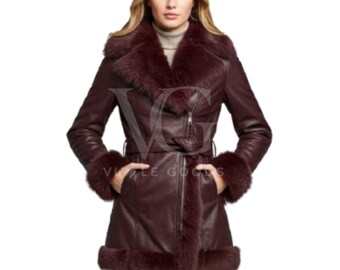 Può includere: Un cappotto in pelle bordeaux con collo, polsini e orlo in pelliccia. Il cappotto presenta una chiusura con zip, una cintura in vita e tasche. La modella indossa un dolcevita. Un capospalla elegante.