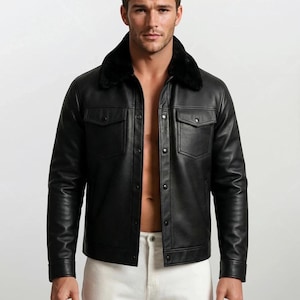 May include: A black leather jacket with a black faux fur collar. The jacket has two chest pockets and is buttoned up. The person in the image is wearing white pants.