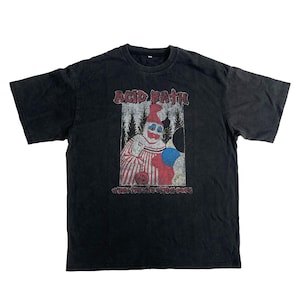 以下が含まれることがあります： 黒いTシャツ。退色したピエロのグラフィックが特徴です。「ACID BATH」の文字がピエロの上に、「WHEN THE BITE IS GONE」が下にあります。ピエロは赤と白のストライプの衣装を着て、風船を持っています。