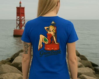 Op de afbeelding: Koning blauw t-shirt met een vintage-stijl grafische afbeelding op de rug. De afbeelding toont een vrouw in een rode jurk, zittend op een rode boei, met de tekst "GrimBeak" eronder. Op de achtergrond is een rode vuurtoren te zien.