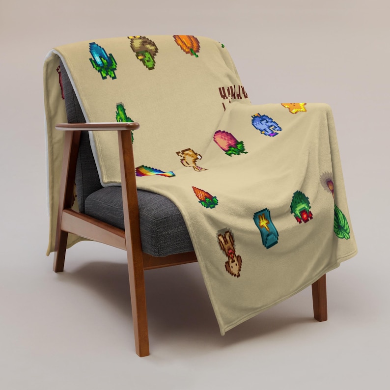 Op de afbeelding: Een beige sprei over een stoel, met een herhaald patroon van kleurrijke gepixelde afbeeldingen van verschillende planten en wezens. De stoel heeft een houten frame en een grijze zitting.