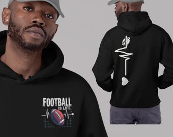Könnte beinhalten: Schwarzer Kapuzenpullover mit dem Text "FOOTBALL IS LIFE" und einer Football-Grafik auf der Vorderseite. Auf der Rückseite befindet sich ein Football- und Herzschlag-Design. Der Kapuzenpullover wird von einer Person getragen, die eine graue Baseballkappe trägt.