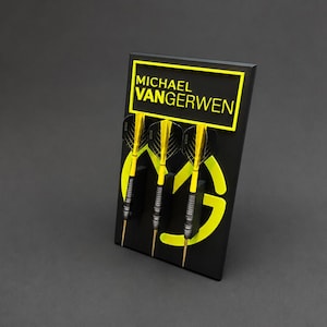 Könnte beinhalten: Ein schwarzer Präsentationsständer mit drei Darts, die gelbe Flights und silberne Barrels aufweisen. Der Ständer zeigt oben den gelben Schriftzug MICHAEL VANGERWEN und in der Mitte ein großes gelbes MVG-Logo zur Präsentation von Dart-Ausrüstung.