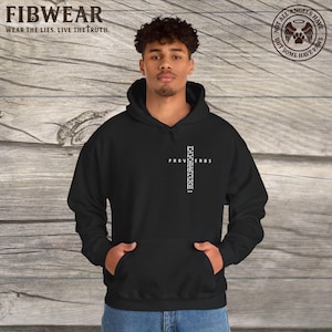 Peut inclure: Sweat à capuche noir avec une poche avant. Le sweat-shirt affiche le mot "PROVERBES" en blanc, formant une croix. La marque "FIBWEAR" est en haut, avec le slogan "WEAR THE LIES. LIVE THE TRUTH."