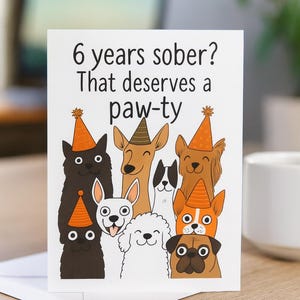 May include: A white greeting card with the text "6 years sober? That deserves a paw-ty" and illustrations of cartoon dogs wearing party hats. The dogs are various colors and breeds.