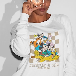 Sweat-shirt à motif damier brun clair Mickey n Co. • Pull ras du cou Disney lumineux • Polaire unisexe dessin animé de style vintage avec Dingo, Minnie, Pluto,