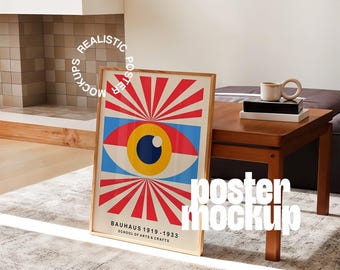 Könnte beinhalten: Ein gerahmtes Poster mit einem geometrischen Augendesign in Rot, Weiß, Blau und Gelb. Der Text "BAUHAUS 1919-1933 SCHOOL OF ARTS & CRAFTS" ist auf dem Poster zu sehen. Es lehnt an einer Wand neben einem Holztisch.