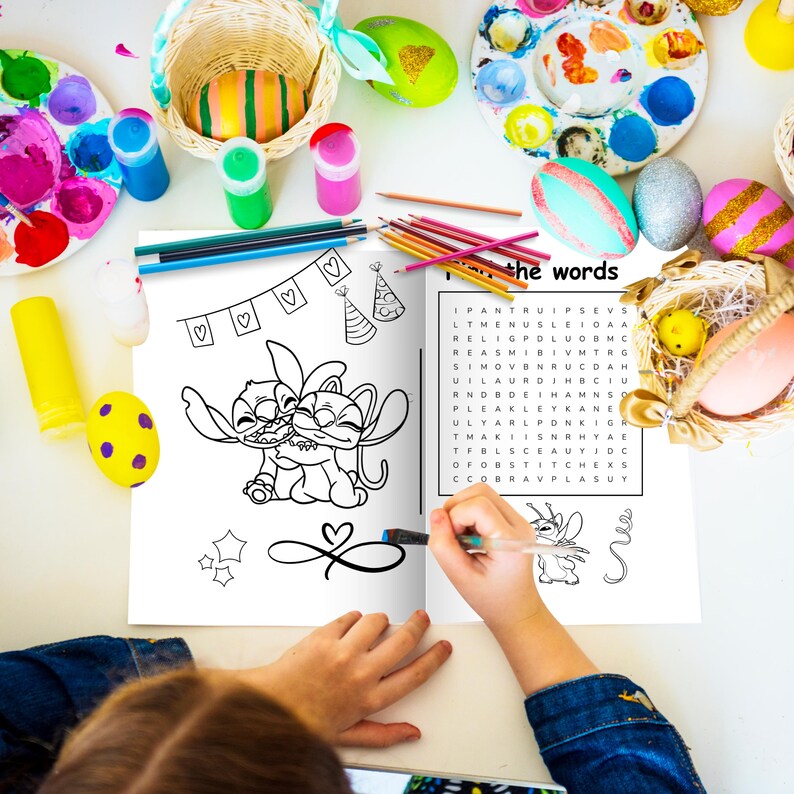 May include: A coloring book with a black and white illustration of two cartoon characters hugging. The book is open, and a hand is holding a pen. Easter eggs, paint, and art supplies surround the book.