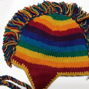 May include: A rainbow striped knitted hat with a long fringe around the brim. The hat is made of wool and has a pointed crown.