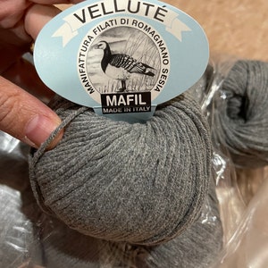 May include: Three skeins of gray yarn in a plastic bag. The yarn is labeled "Velluté" and "Mafil Made in Italy".