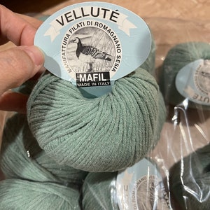 May include: Four skeins of green yarn with a label that reads "Vellut&eacute; Manifattura Filati di Romagna Sesia Mafil Made in Italy".
