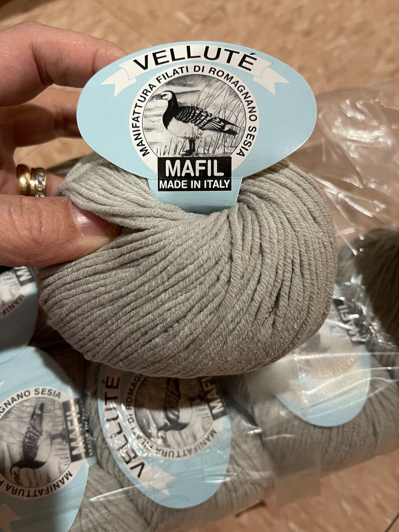 May include: A skein of gray yarn with a label that reads "Vellut&eacute; Manifattura Filati di Romagna Sesia Mafil Made in Italy".