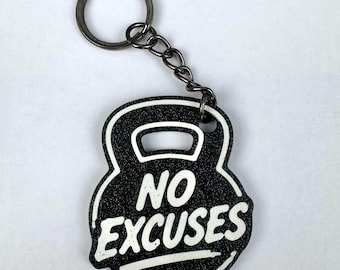 Puede incluir: Un llavero negro con forma de pesa rusa, superficie texturizada y letras blancas que dicen NO EXCUSES. El llavero cuenta con una anilla metálica sujeta por una cadena corta de metal, sirviendo como un accesorio funcional para las llaves.