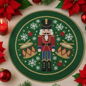 Op de afbeelding: Een groene, met kralen bezette kerstplacemat met een notenkrakersoldaat in een rood uniform, zwarte laarzen en een zwarte hoed. Het ontwerp bevat sneeuwvlokken, ornamenten en trommels. Rode poinsettia's en ballen omringen de placemat.