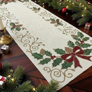 May include: Cream-colored beaded Christmas table runner with a festive design. Features green holly leaves, red berries, and a burgundy bow. Gold-colored pinecones and decorative swirls complete the holiday look.