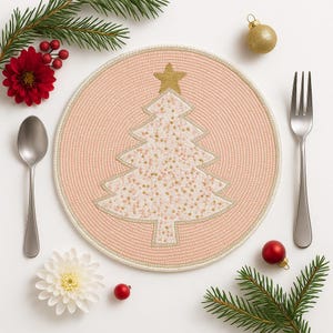 May include: A round, pink beaded placemat with a white Christmas tree design and a gold star on top. The placemat is surrounded by a silver spoon, fork, red ornaments, and sprigs of greenery, creating a festive holiday scene.