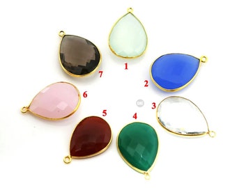 May include: Seven teardrop-shaped gemstone pendants with gold-plated settings. The gemstones are clear, green, red, pink, blue, gray, and white.