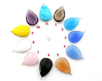 May include: Twelve teardrop-shaped gemstone pendants with silver bail settings. The gemstones are in various colors, including blue, purple, yellow, white, pink, black, brown, and clear.