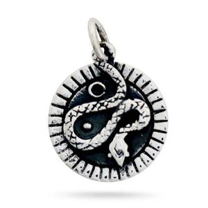 以下が含まれることがあります： 黒い背景に円形に巻き付いた蛇が描かれたシルバーチャーム。円形には装飾的な縁取りが施されています。