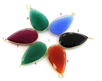 May include: A collection of teardrop-shaped pendants in various colors, including blue, black, red, and green. Each pendant has a gold-colored bezel and a small loop for attaching to a chain or other jewelry component. The pendants are arranged in a circular pattern.