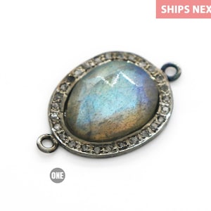 May include: Oval-shaped labradorite gemstone pendant with a silver bezel and a diamond halo. The pendant has two jump rings for attaching to a chain or cord.